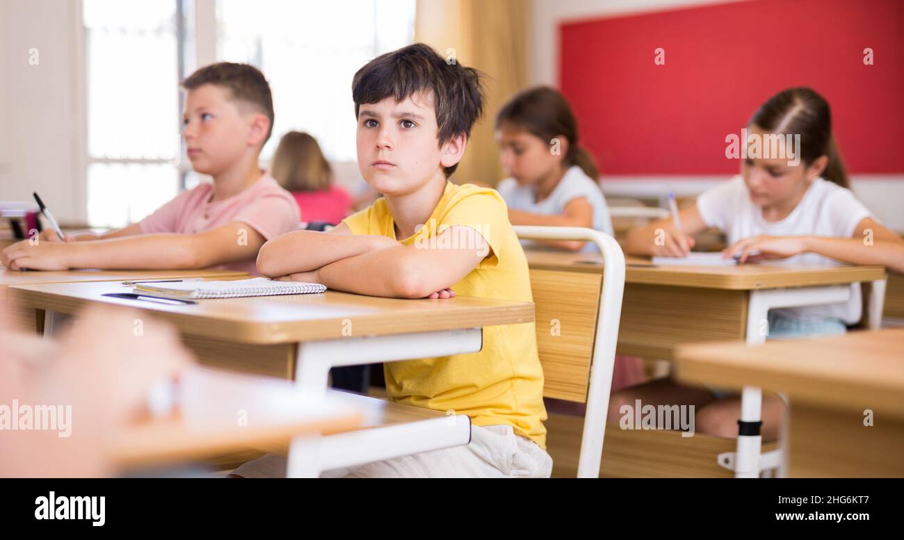 Jeune garçon diligent étudiant avec des camarades de classe à l'école Banque D'Images