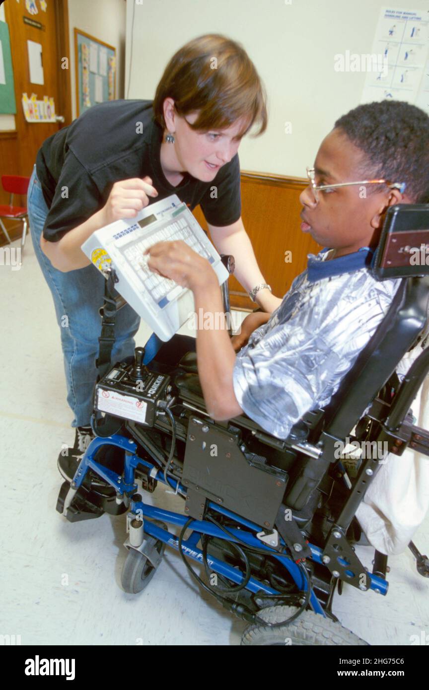 New Jersey East Orange, centre de paralysie cérébrale, fauteuil roulant électrique handicapé, femme étudiante, thérapeute, clavier d'ordinateur communicateur de garçon noir Banque D'Images