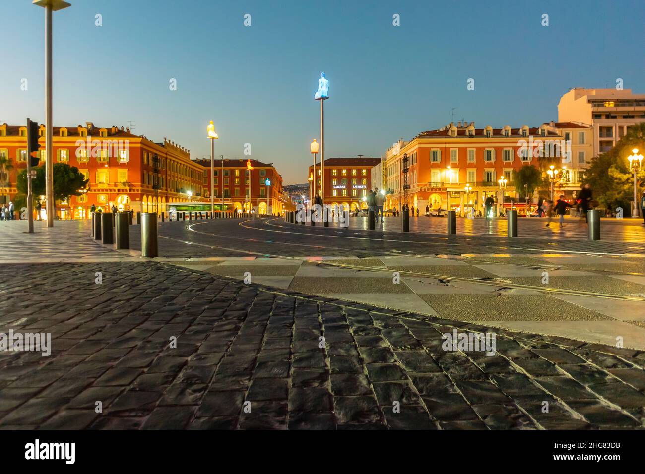 Nice, France, vue grand angle, scène de rue, nuit, paysages urbains, lumières, 'la conversation à Nice' sculpture moderne de l'artiste espagnol 'Jaume Plensa' est situé des deux côtés de la ligne de tramway qui traverse la 'place Massena' belle vieille ville Banque D'Images