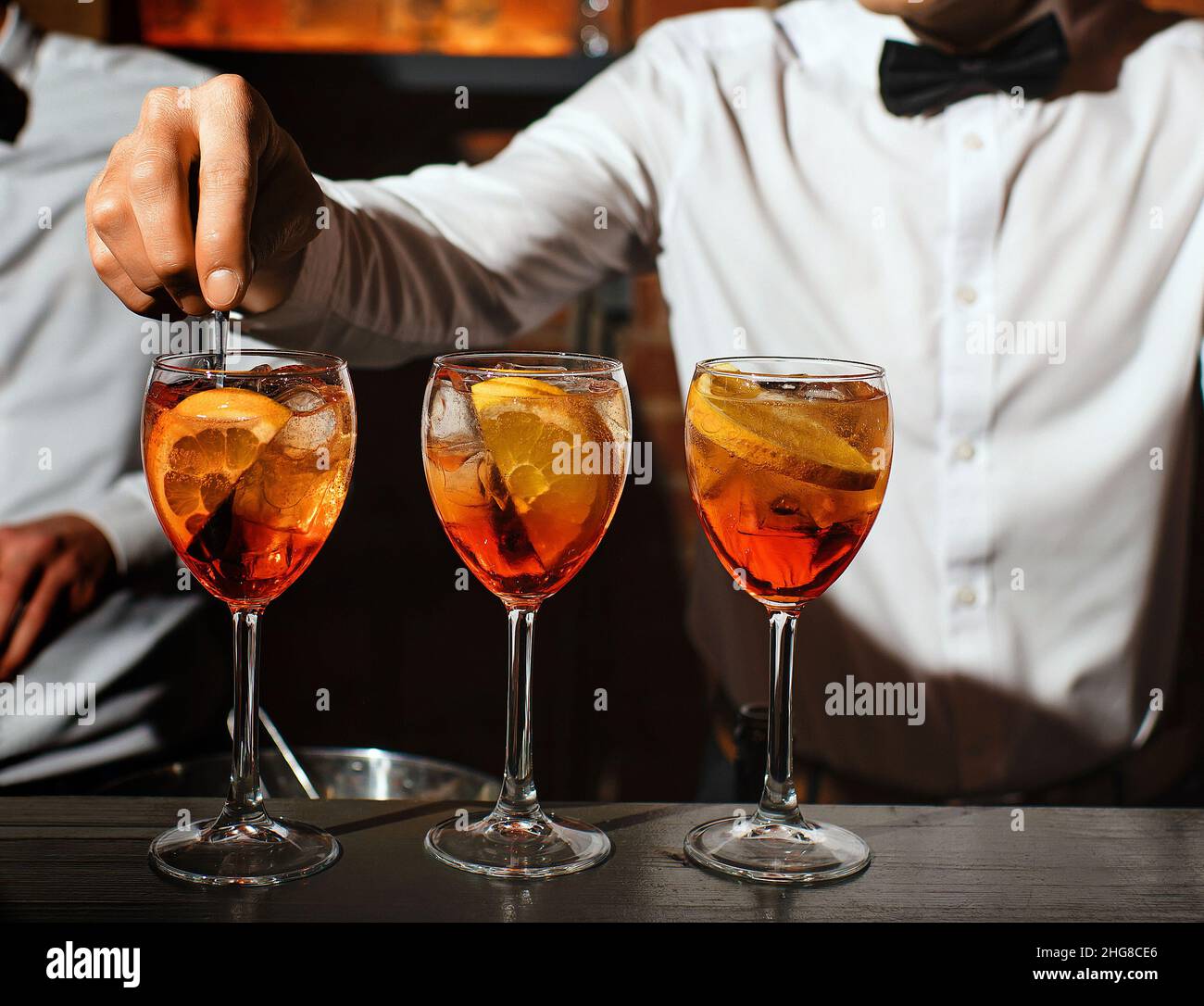 trois verres de verre avec un cocktail aperol spritz sont sur le bar barman est remuant un des apéritifs Banque D'Images