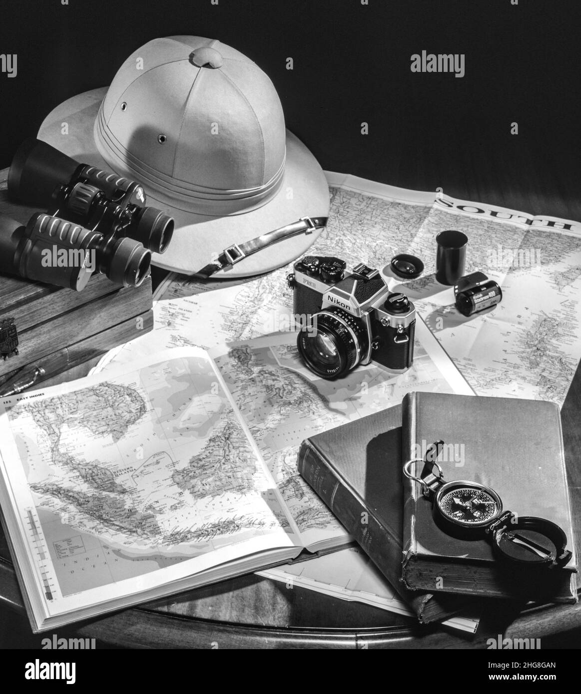 concept de voyage, avec appareil photo rétro et film, livres, cartes, chapeau de safari, boussole et jumelles sur une table en verre en bois Banque D'Images