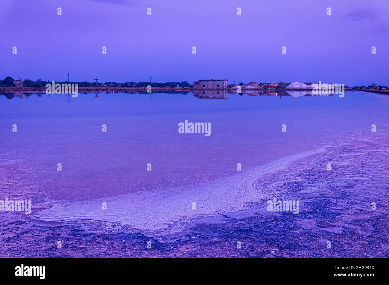 Cervia sel plat au crépuscule avec dépôts de sel sur le sol et usine en arrière-plan Banque D'Images