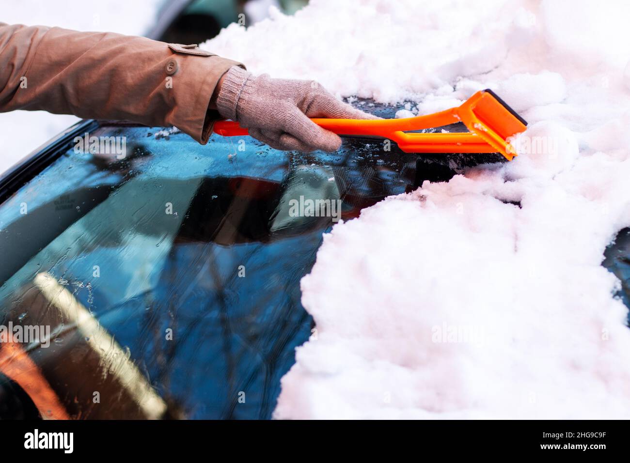 Une fille qui enlève la neige et la glace de la voiture Banque D'Images