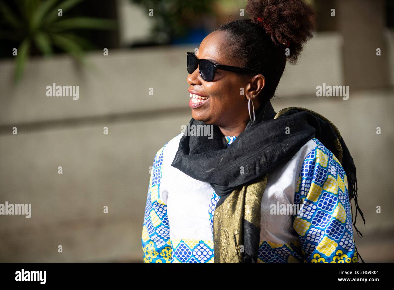 femme d'affaires portant des lunettes de soleil avec foulard autour de son  cou, regardant de côté dans la rue souriant Photo Stock - Alamy