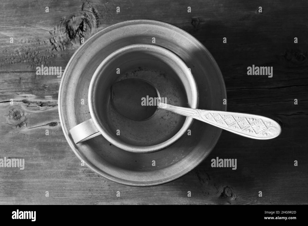 Vider le plat en aluminium, la cuillère et le mug sur l'ancienne table en bois, noir et blanc Banque D'Images