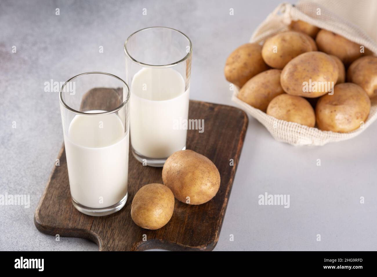 Lait à base de légumes dans deux verres transparents.Lait de pomme de terre de remplacement et tubercules de pomme de terre sur table grise Banque D'Images