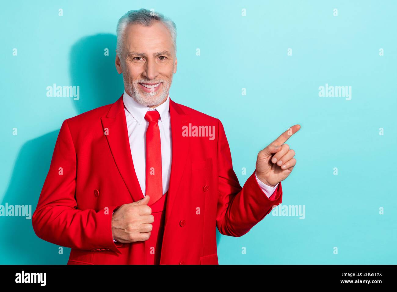 Photo de charmant retraité homme porter un costume rouge trois pièces pointant espace vide isolé turquoise couleur arrière-plan Banque D'Images