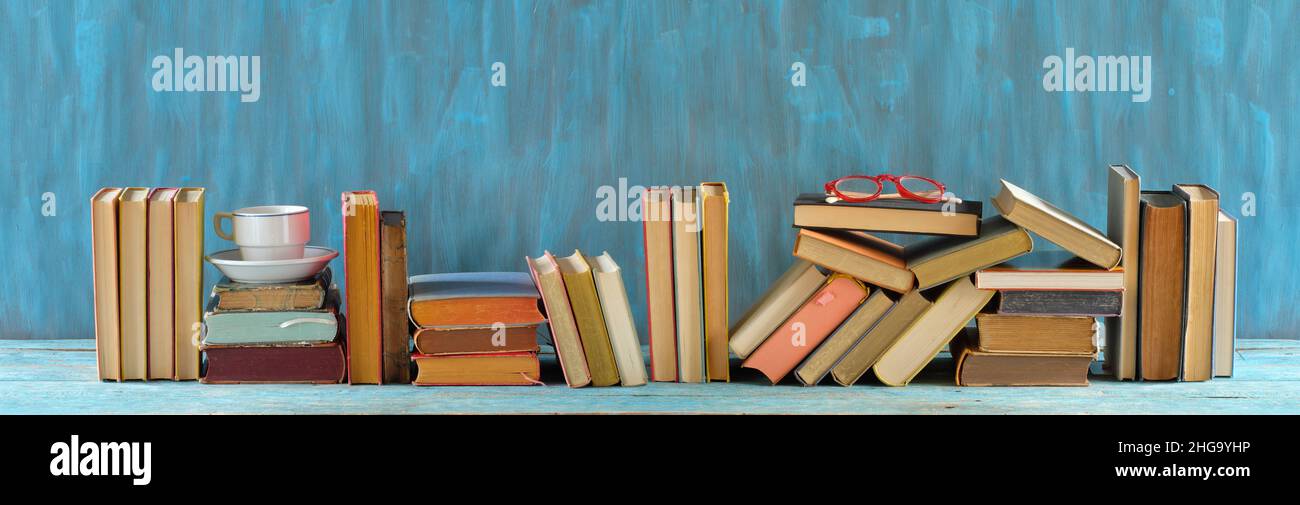 rangée de livres, livres en bois sur table en bois sur fond bleu.Retour à l'école, l'éducation, la lecture, le bureau à domicile.Panoramique, grand espace de copie libre Banque D'Images