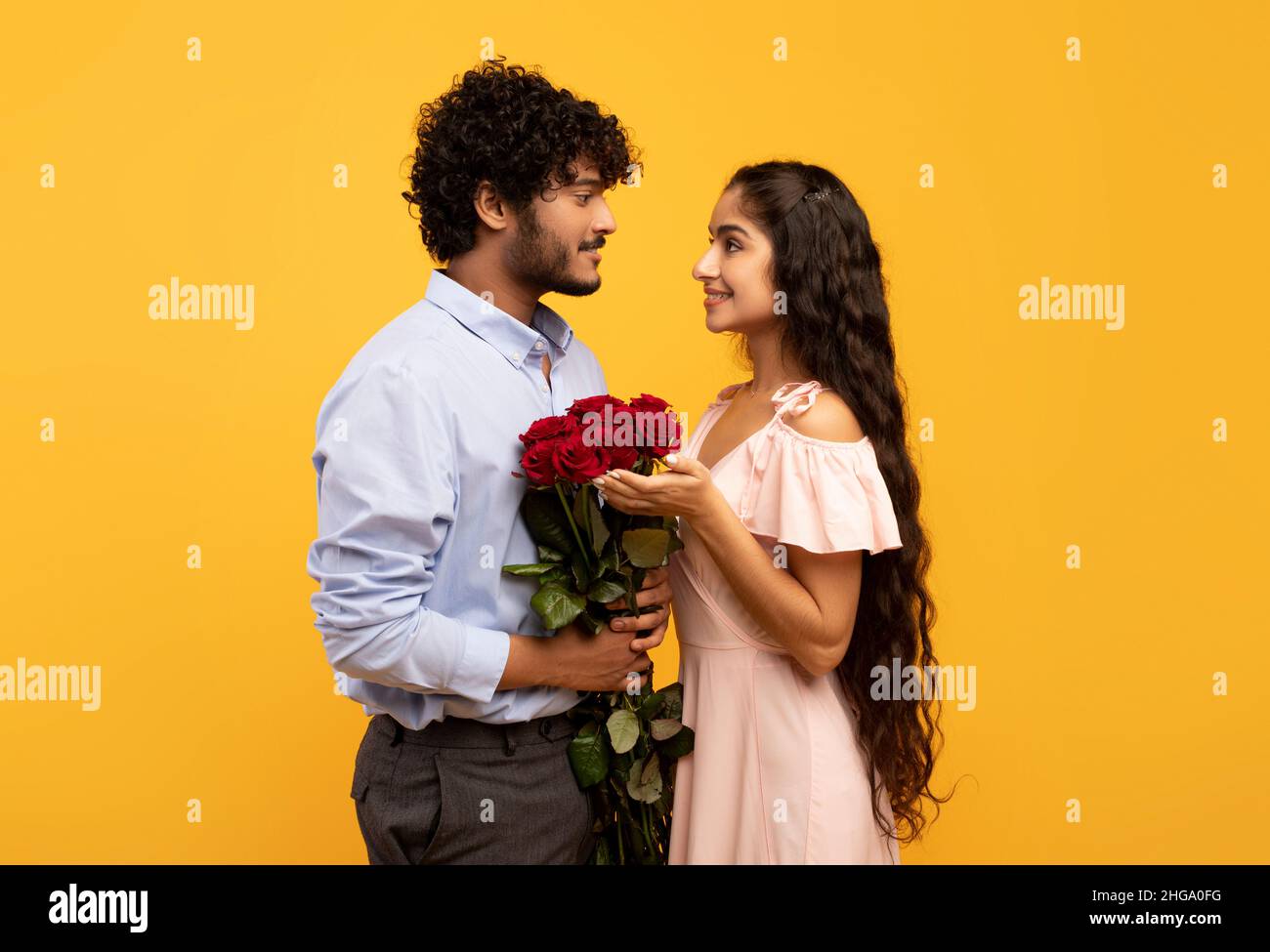 Romantique conjoints indiens tenant un bouquet de fleurs et regardant l'un l'autre, gars choyer sa petite amie avec des roses Banque D'Images
