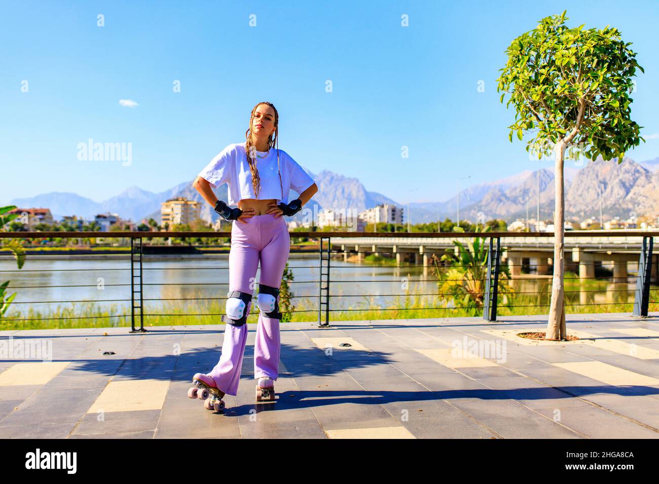 Femme heureuse avec de longs cheveux blonds sur le roller-skate sur la plage du parc et le fond de la montagne Banque D'Images Femme heureuse avec de longs cheveux blonds sur le roller-skate sur la plage du parc et le fond de la montagne Banque D'Images