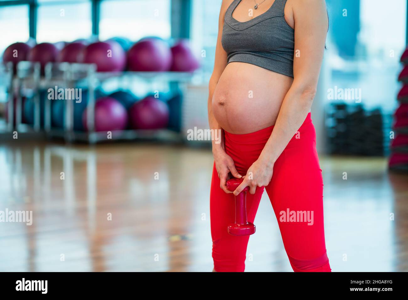 Torse de femme enceinte dans les vêtements de sport s'exerçant avec des haltères dans la salle de gym.Soins de santé et contrôle du poids concept de grossesse Banque D'Images