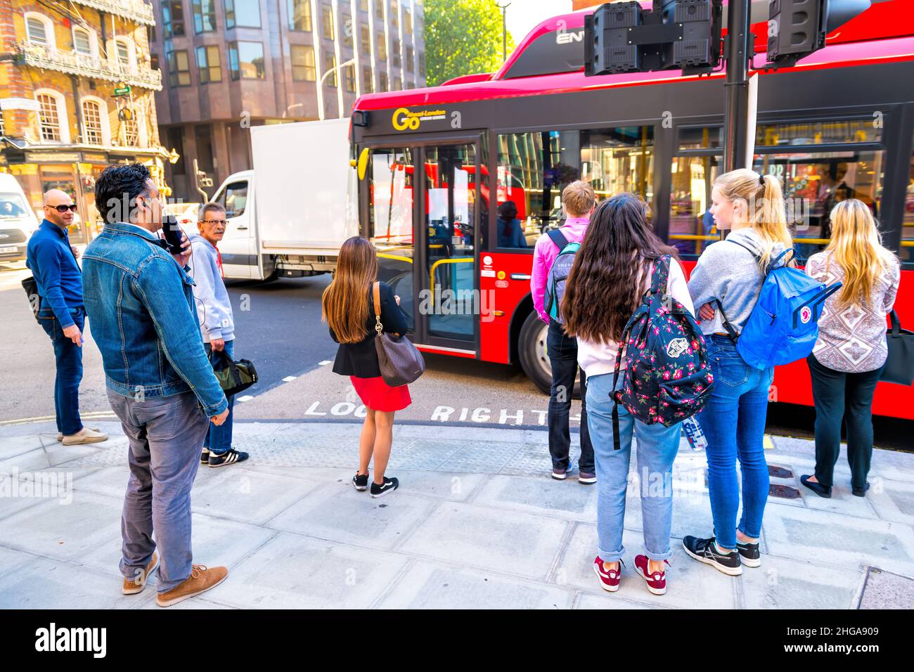 Londres, Royaume-Uni - 22 juin 2018 : arrêt de bus avec des personnes en attente d'embarquement ou de traverser le trottoir de la rue avec bus rouge pour les trajets quotidiens de la vie urbaine de Lo Banque D'Images