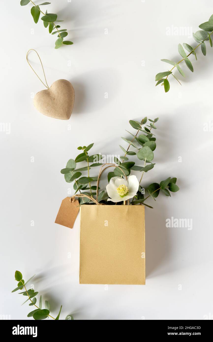 Sac d'artisanat avec eucalyptus hivernal et fleur d'Helleborus blanche.Étiquette  en papier marron et coeur en carton.Couche plate d'hiver avec brindilles à  feuilles persistantes Photo Stock - Alamy