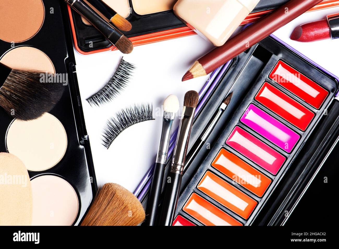 Fonds de teint, poudre, correcteur, pinceaux de maquillage, éponges de maquillage,faux cils, rouge à lèvres, doublure pour les lèvres, mascara sur fond blanc Banque D'Images