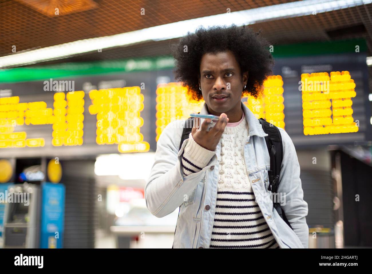 Jeune Africain américain avec une coiffure afro parlant au téléphone.Il est dans un terminal d'aéroport.Espace pour le texte. Banque D'Images