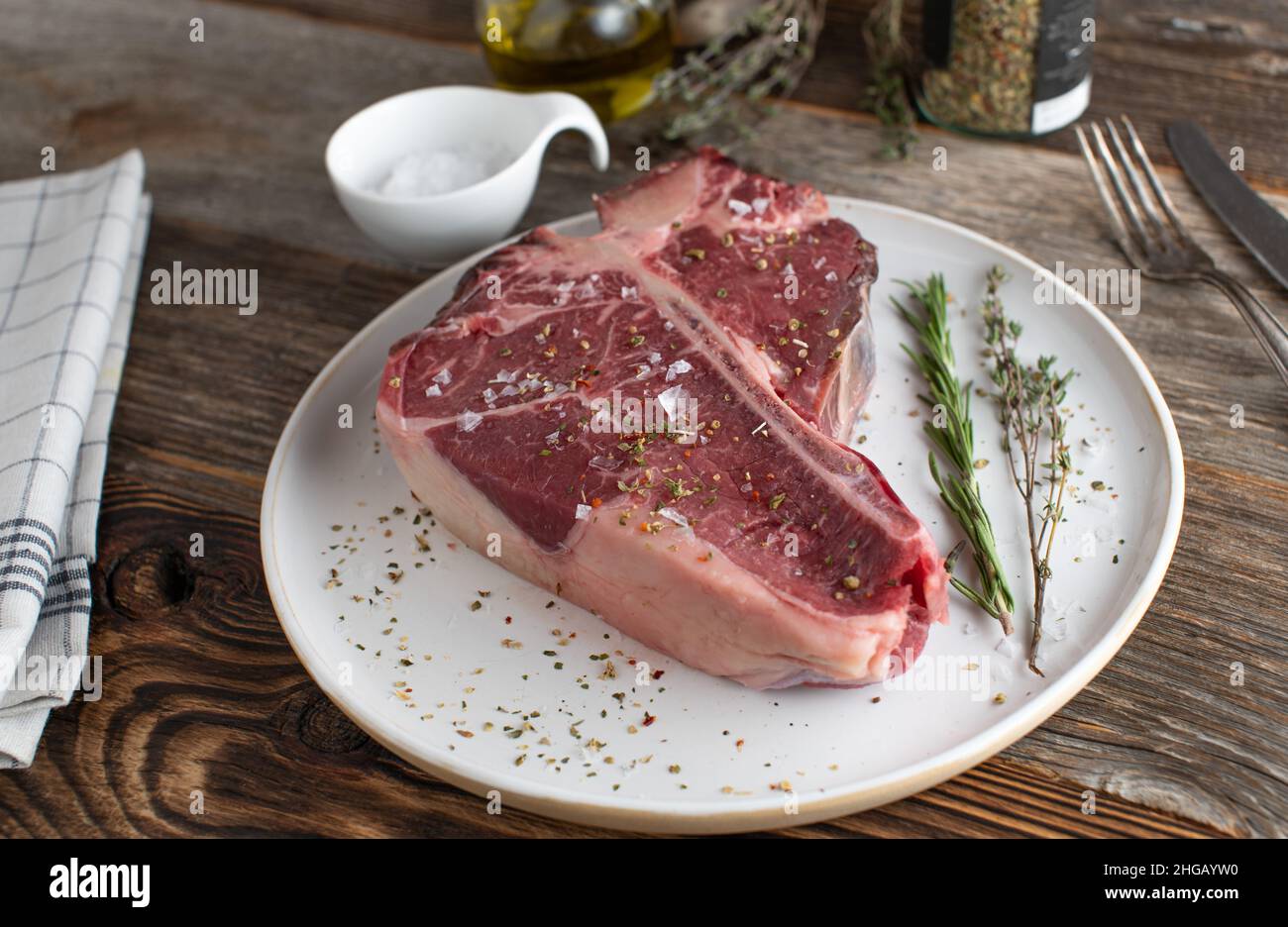 Steak de Porterhouse sec et cru avec des assaisonnements et des herbes Banque D'Images