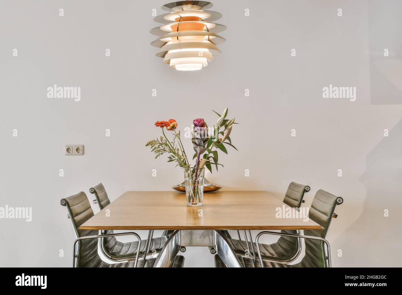 Salle à manger confortable et élégante avec un lustre design et un vase de fleurs sur la table Banque D'Images