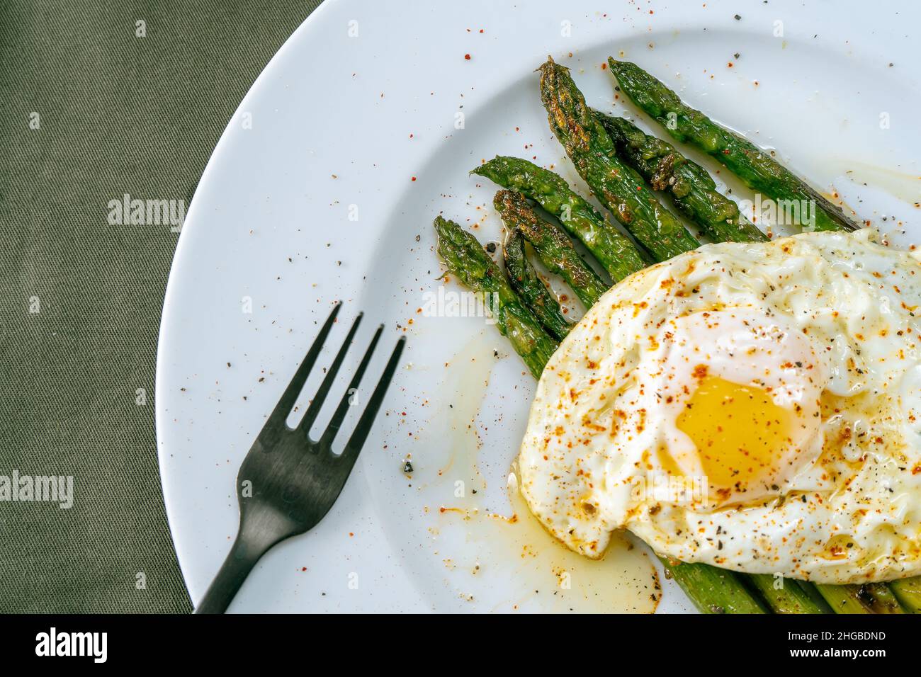 Une exquise asperge cuite préparée avec un œuf frit, assaisonnée et épicée.Cuisine naturelle, gastronomique. Banque D'Images