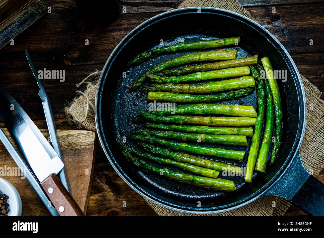 Délicieux préparation d'asperges vertes cuites au beurre dans une casserole sur un comptoir en bois. Banque D'Images