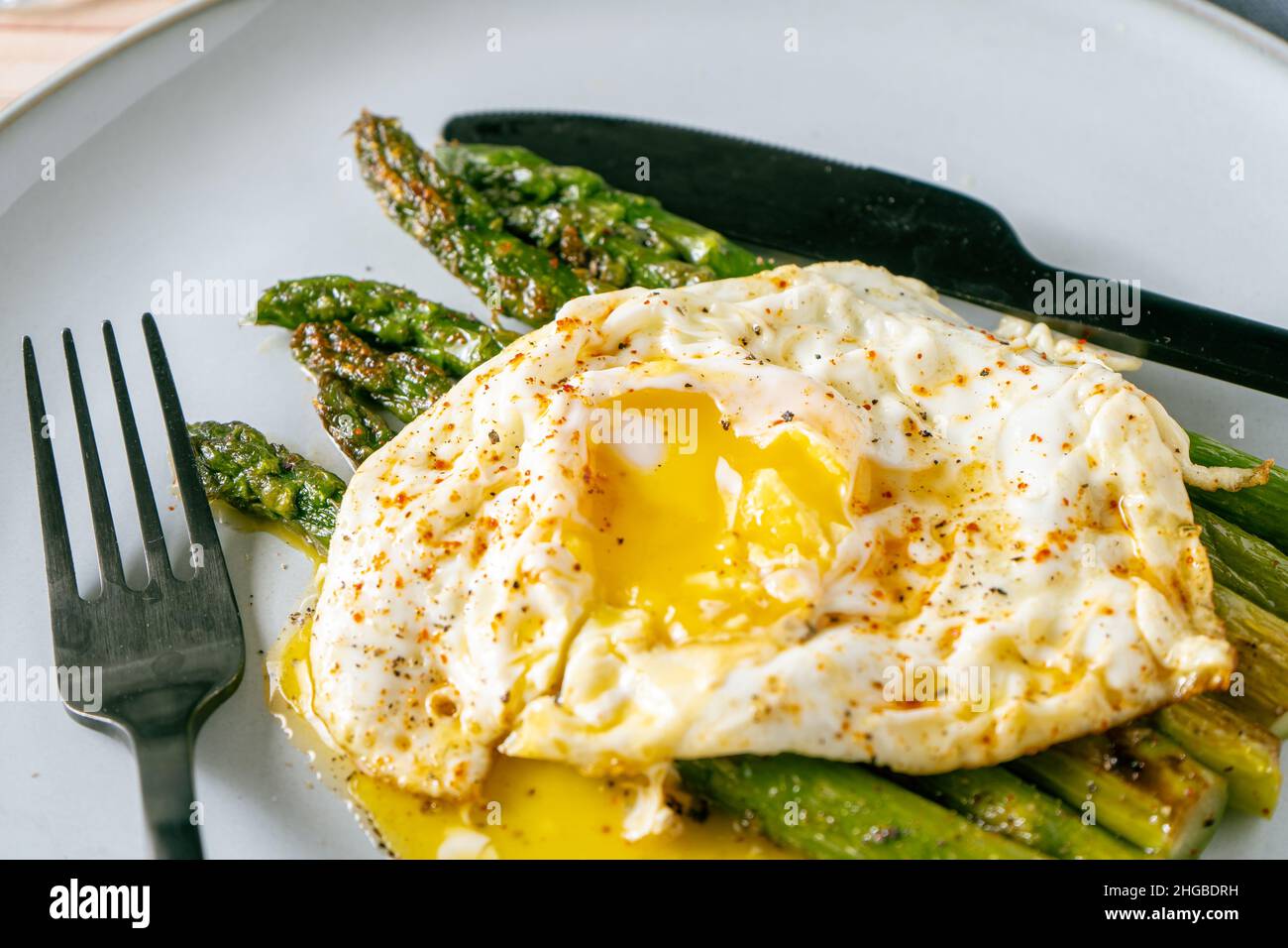 Une exquise asperge cuite préparée avec un œuf frit, assaisonnée et épicée.Cuisine naturelle, gastronomique. Banque D'Images