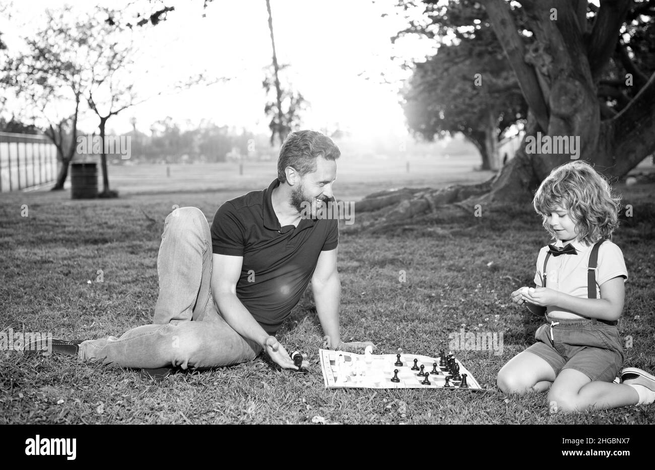 père et fils jouent aux échecs sur l'herbe dans le parc d'été, paternité Banque D'Images