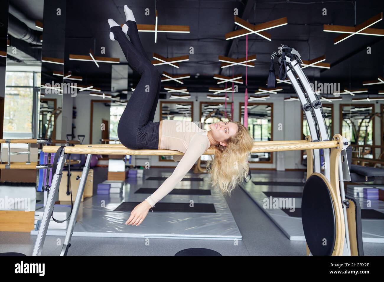 Vue latérale d'une femme athlétique ayant pilates séance d'entraînement dans un studio moderne en journée.Sport, mode de vie actif, concept d'étirement Banque D'Images