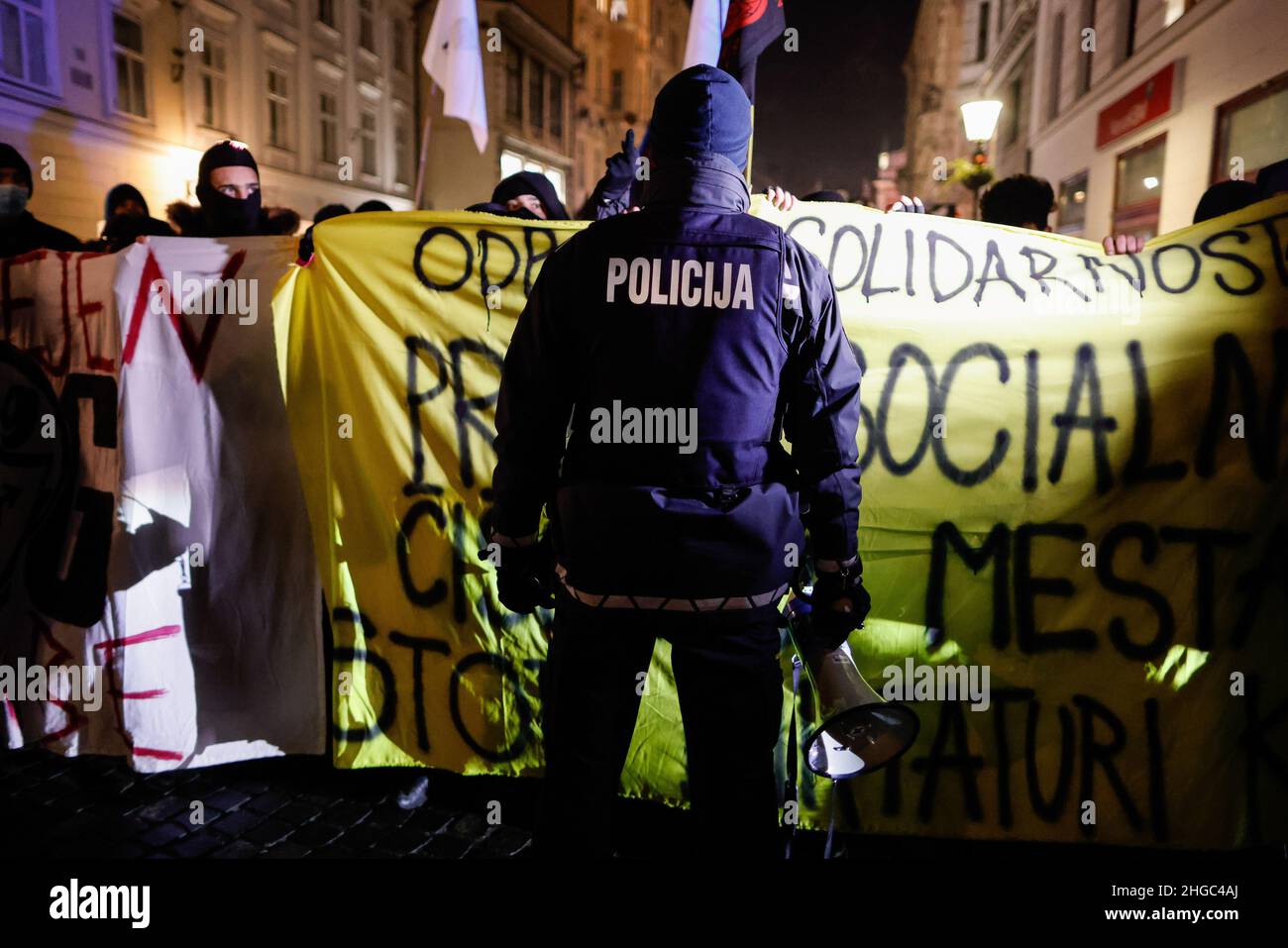 Ljubljana, Slovénie.19th janvier 2022.Un policier se tient devant les manifestants, portant des banderoles pendant la manifestation.Lors du premier anniversaire des expulsions controversées d'artistes et de centres culturels d'une ancienne usine de vélos ragé de Ljubljana, les manifestants ont de nouveau protesté contre la privatisation et la commercialisation croissantes de l'espace public et le nettoyage social de la ville qui pousse les citoyens, en particulier ceux à faible revenu, à l'extérieur.Crédit : SOPA Images Limited/Alamy Live News Banque D'Images