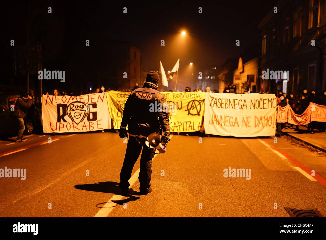 Ljubljana, Slovénie.19th janvier 2022.Un policier se tient devant les manifestants, portant des banderoles pendant la manifestation.Lors du premier anniversaire des expulsions controversées d'artistes et de centres culturels d'une ancienne usine de vélos ragé de Ljubljana, les manifestants ont de nouveau protesté contre la privatisation et la commercialisation croissantes de l'espace public et le nettoyage social de la ville qui pousse les citoyens, en particulier ceux à faible revenu, à l'extérieur.Crédit : SOPA Images Limited/Alamy Live News Banque D'Images
