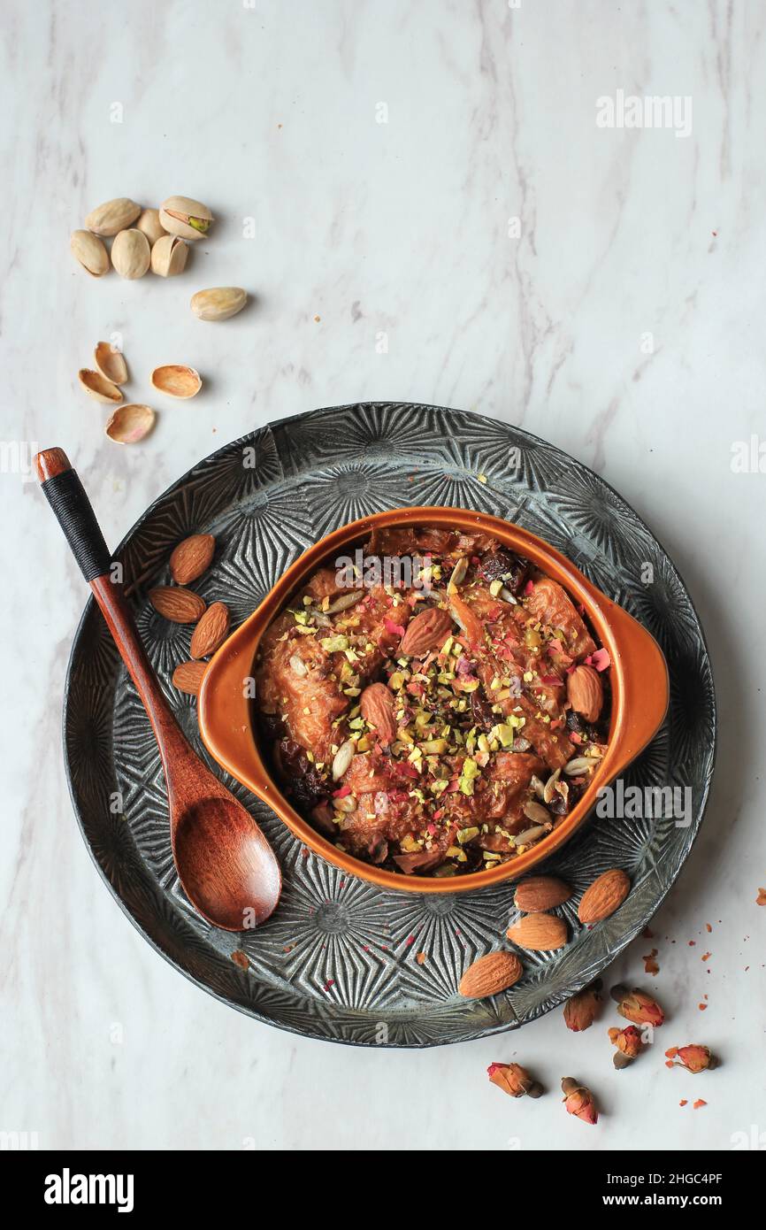 OM Ali ou Umm Ali, pain de pâtisserie trempé, lait, et charge de noix rôties et raisins secs.Surmontée d'un pétales de rose, vue de dessus avec espace de copie Banque D'Images