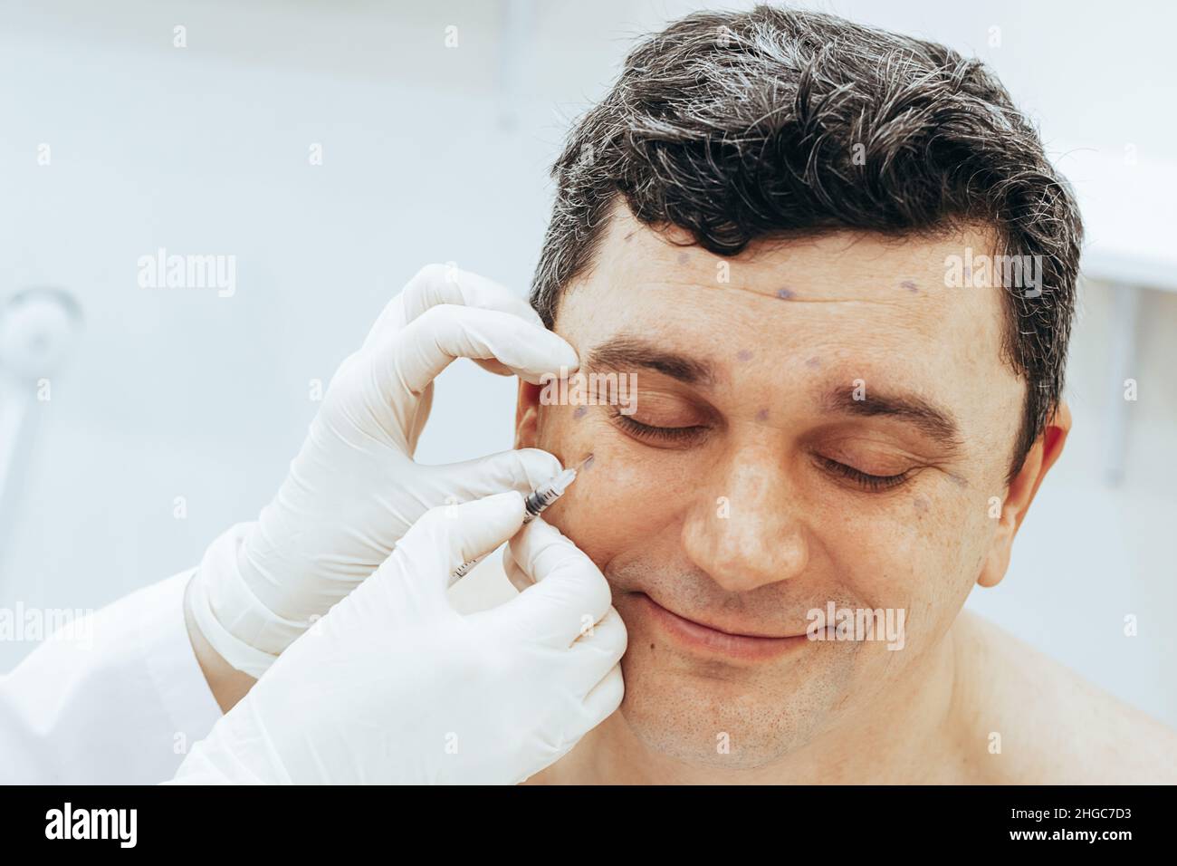 Le cosmétologue effectue une procédure de rajeunissement met Botox injection sur l'homme.Le concept des soins rajeunissants Banque D'Images