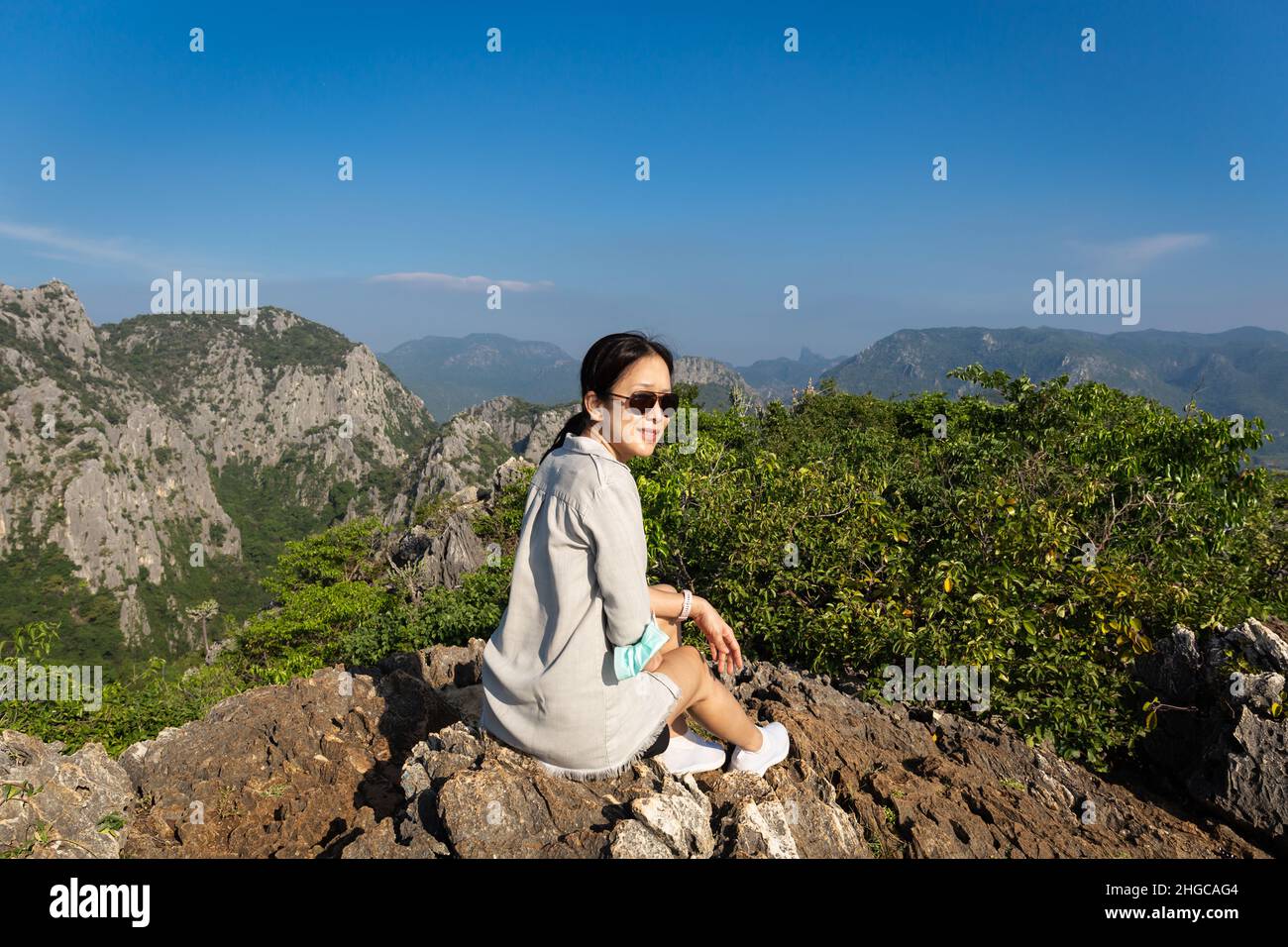 Femme asiatique avec des lunettes de soleil assis sur le sommet de la montagne. Banque D'Images