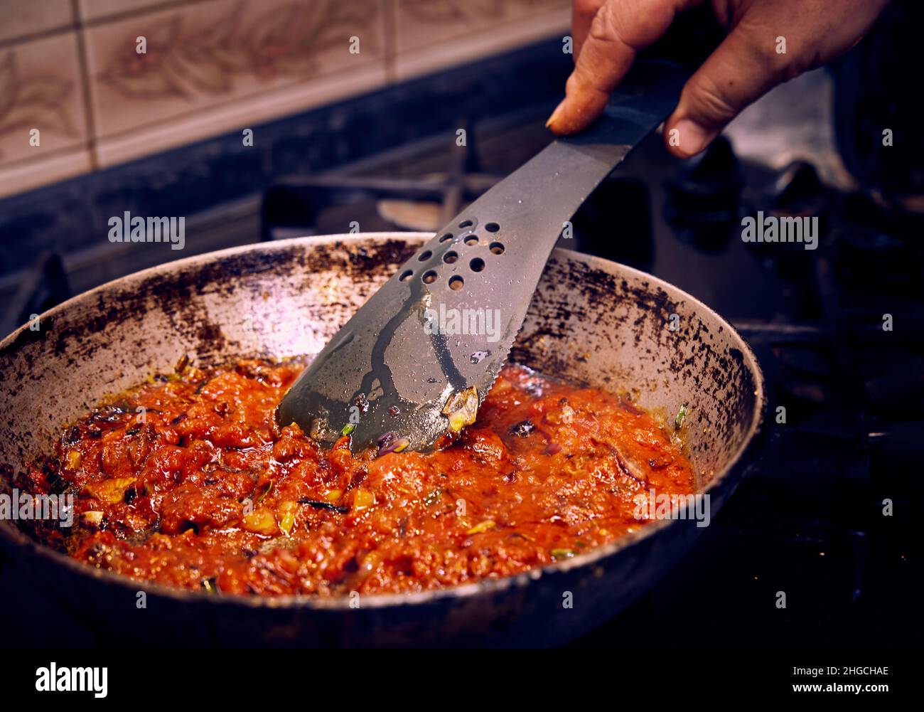 La sauce tomate aux champignons, aux oignons et à l'huile d'olive est frite dans une poêle à gaz de cuisine. Banque D'Images