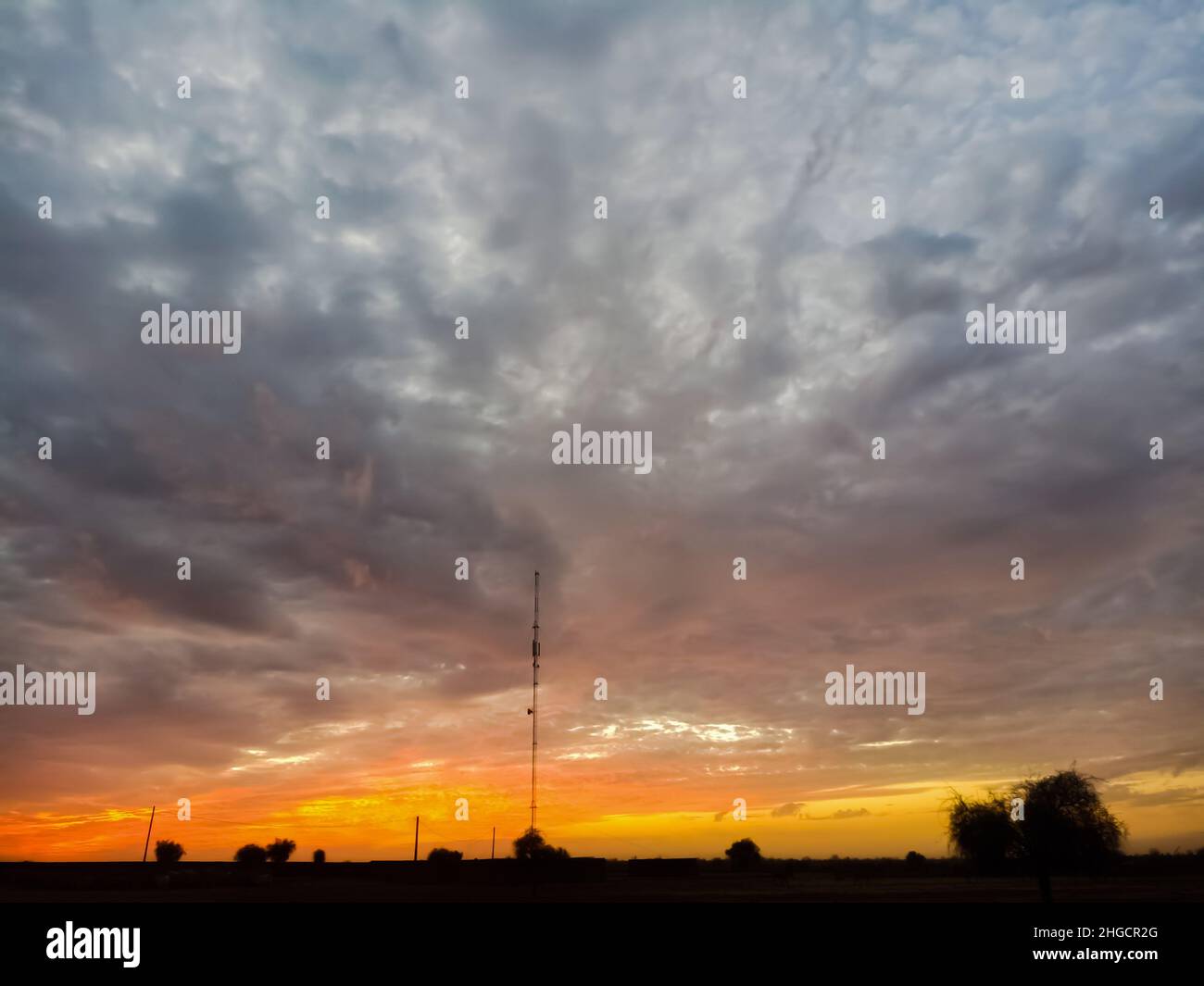 Magnifique coucher de soleil dans le village et nuages blancs dans le ciel orange et bleu Banque D'Images