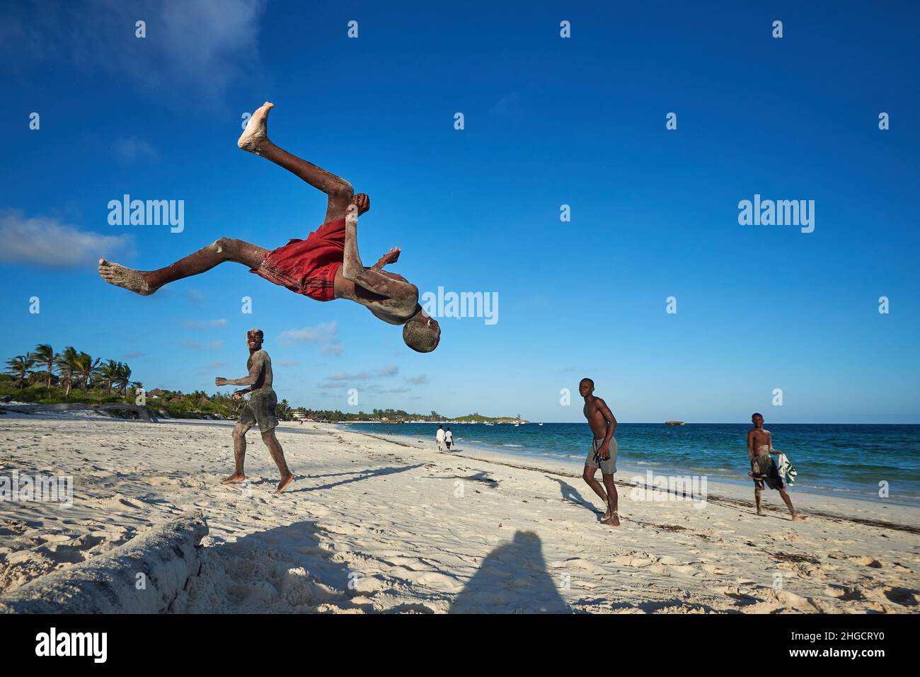 Garçon exécutant action saut acrobatique de jeunes hommes africains rotation aérienne d'un homme sur la plage à Watamu, Kenya, Afrique saut jeune homme Banque D'Images