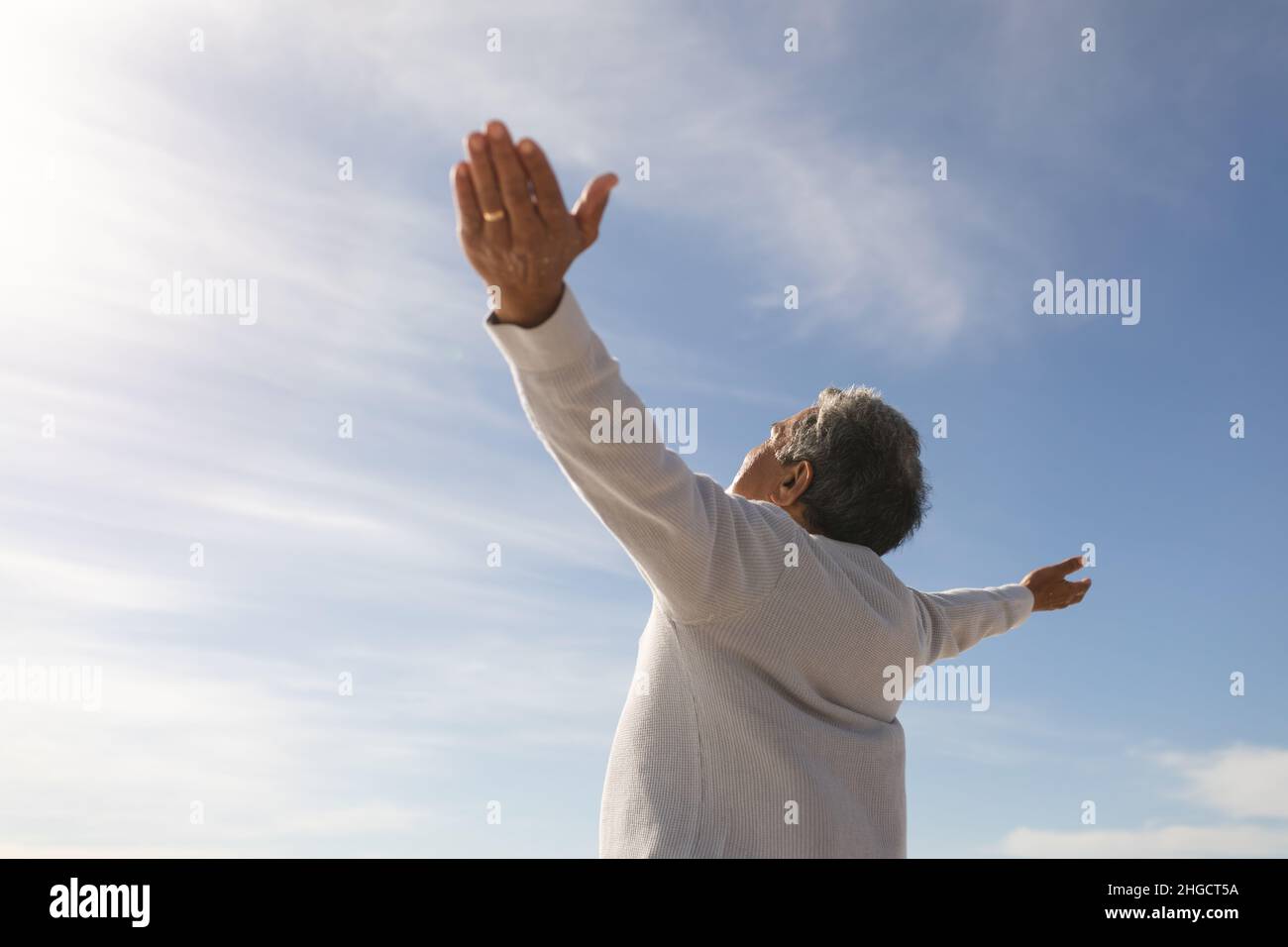 Vue à angle bas de l'homme biracial insouciant avec les bras étendus sous le ciel par jour ensoleillé Banque D'Images