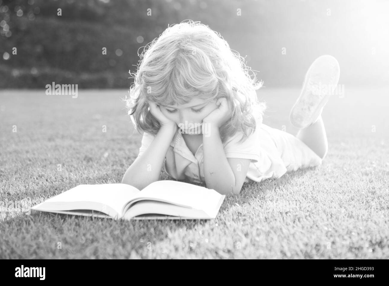 Enfants intelligents.Garçon lisant le livre d'intérêt dans le jardin.L'été s'amuser.Adorable garçon allongé sur l'herbe lisant un livre pour enfants.Concept de l'apprentissage des enfants, l'étude Banque D'Images