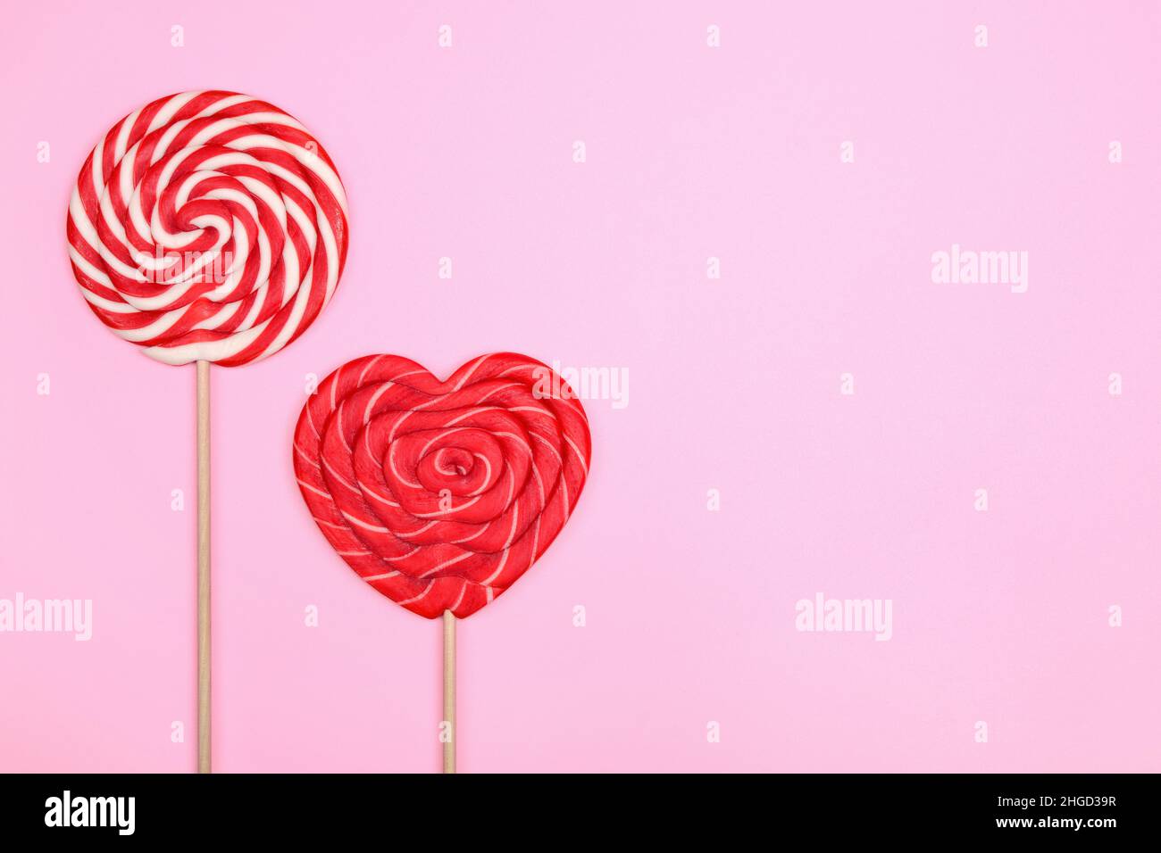 Bonbon rond à deux tons et une boucle rouge en forme de coeur sur fond rose. Banque D'Images