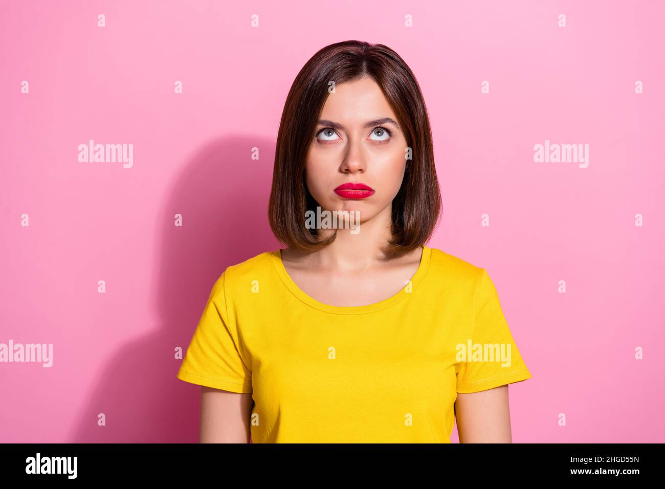 Portrait d'une jolie fille à cheveux bruns brochée à la recherche isolée sur fond rose pastel Banque D'Images