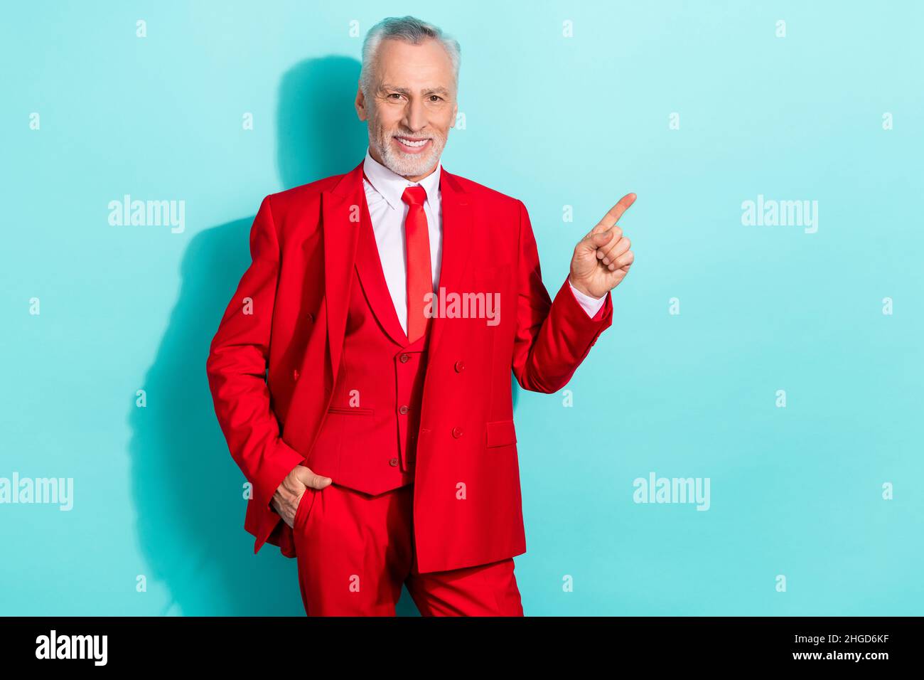 Photo d'un homme à la retraite confiant porter un costume rouge trois pièces pointant l'espace vide isolé couleur turquoise arrière-plan Banque D'Images