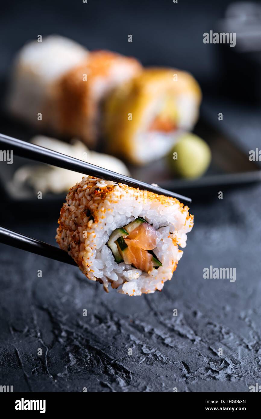 Divers petits pains à sushis sur fond sombre avec baguettes, wasabi et sauce soja.Cuisine traditionnelle japonaise de rue Banque D'Images