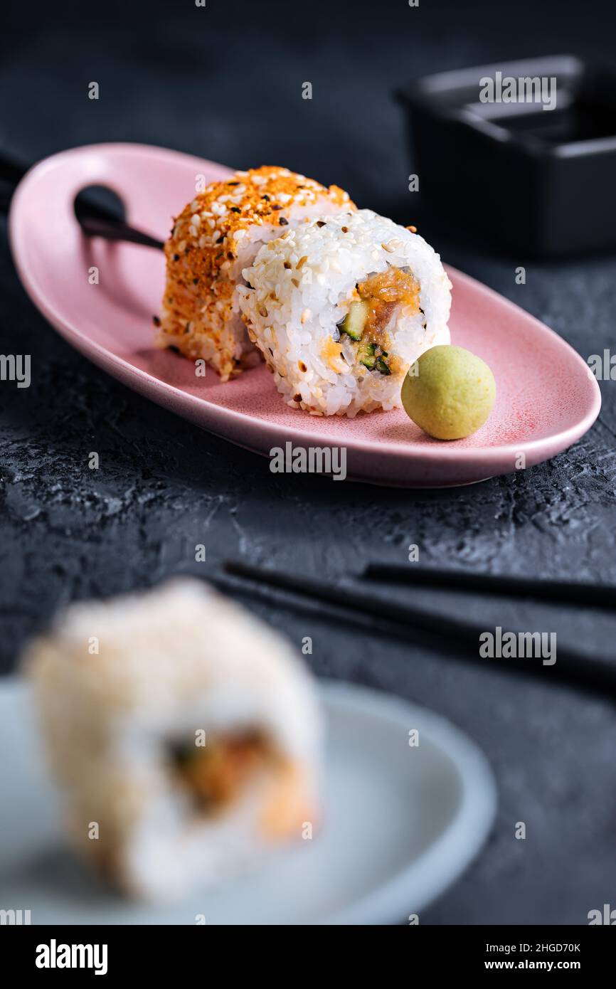 Divers petits pains à sushis sur fond sombre avec baguettes, wasabi et sauce soja.Cuisine traditionnelle japonaise de rue Banque D'Images