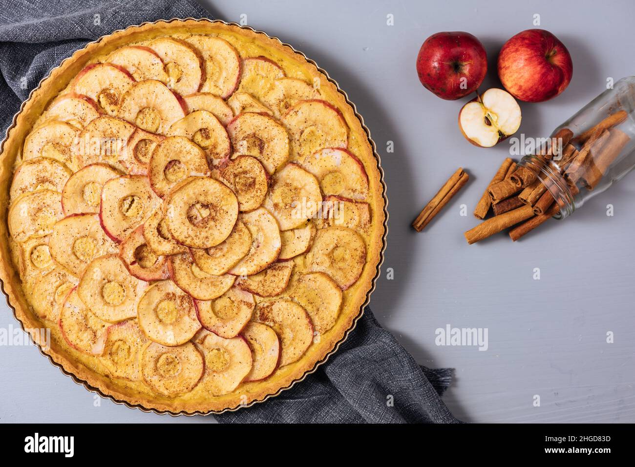 Vue de dessus de la tarte aux pommes française classique sur fond gris avec pommes et bâtons de cannelle Banque D'Images