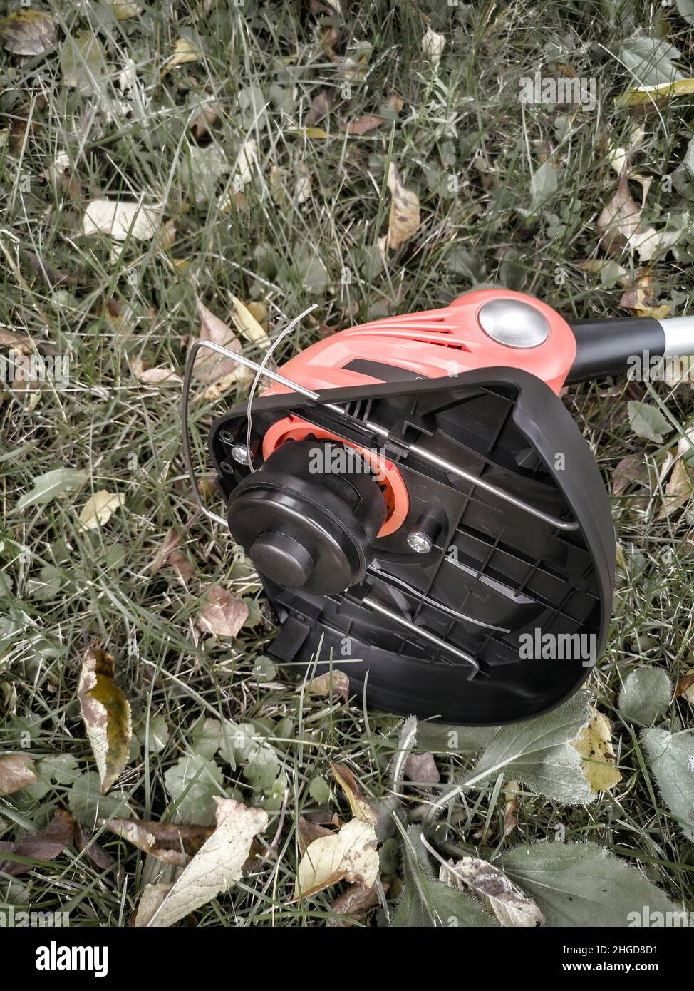 Appareils électroménagers : tondeuse-tondeuse pour couper des pelouses sur des batteries rechargeables.Présenté sur un fond d'herbe et de feuilles, vue avant, Banque D'Images