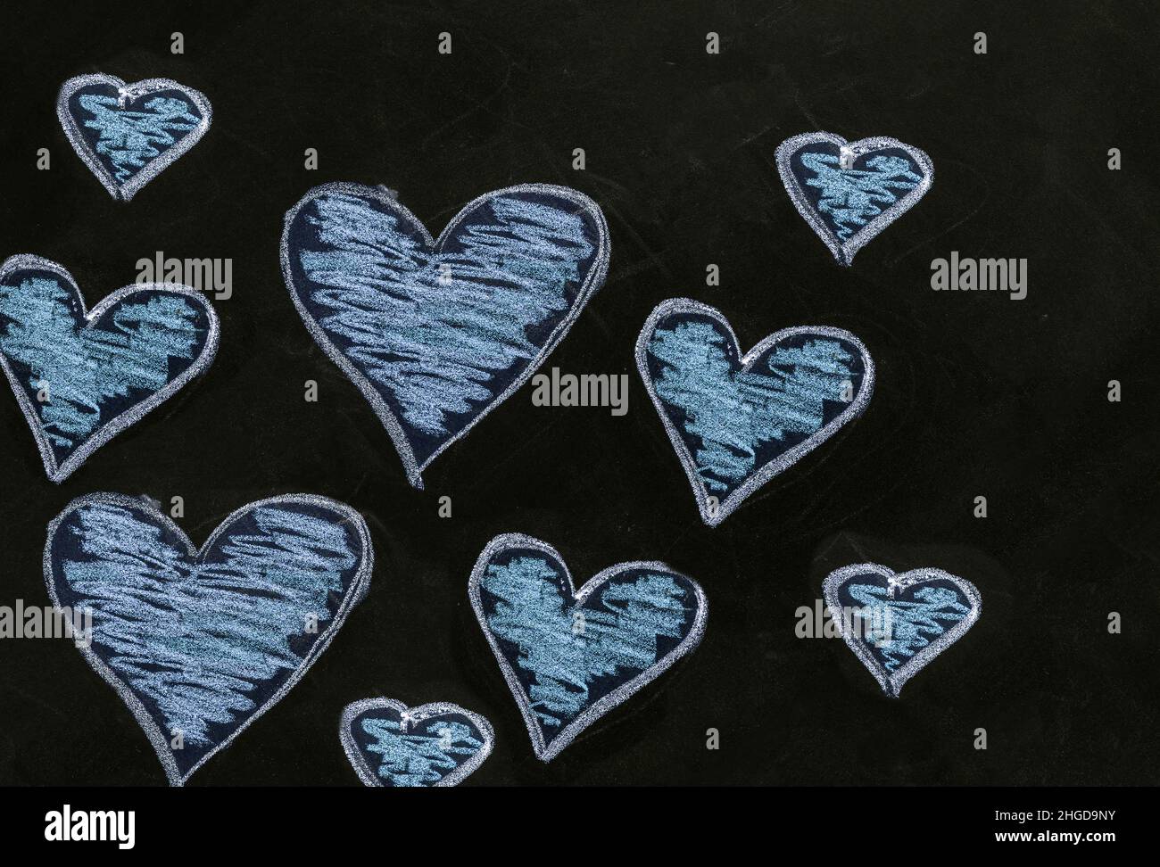 Motif coeur sur le tableau noir de l'école.Amour, symbole de Saint-Valentin.Un groupe de coeurs de couleur bleue dessinés à la main de différentes tailles sur tableau noir Banque D'Images