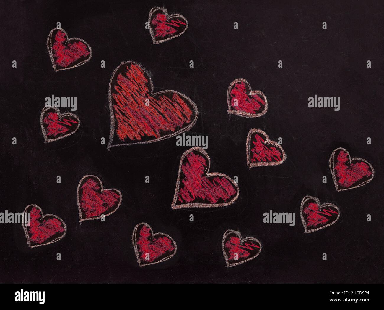 Coeur rouge sur tableau noir de l'école.Amour, symbole de Saint-Valentin.Un groupe de coeurs dessinés à la main de différentes tailles de motif sur le tableau noir Banque D'Images