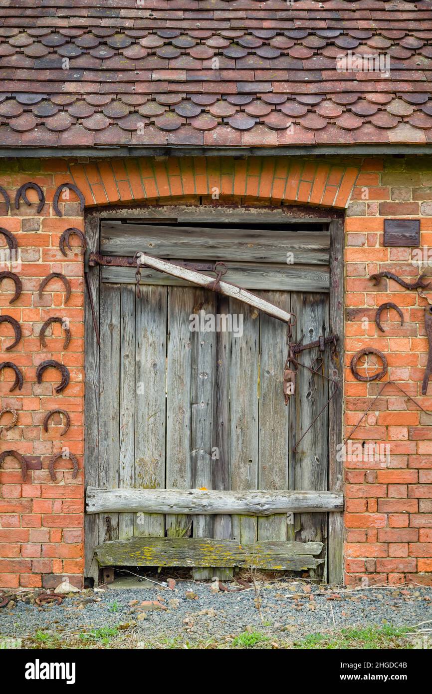 Ancien bâtiment stable avec porte stable en bois.Décoration murale avec fers à cheval, Royaume-Uni Banque D'Images