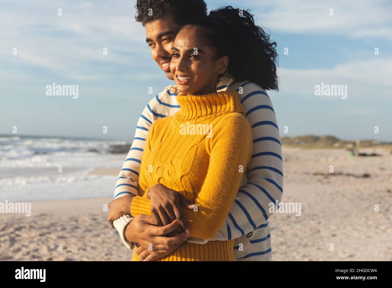 Heureux couple multiracial s'embrassant en regardant la plage contre le ciel Banque D'Images
