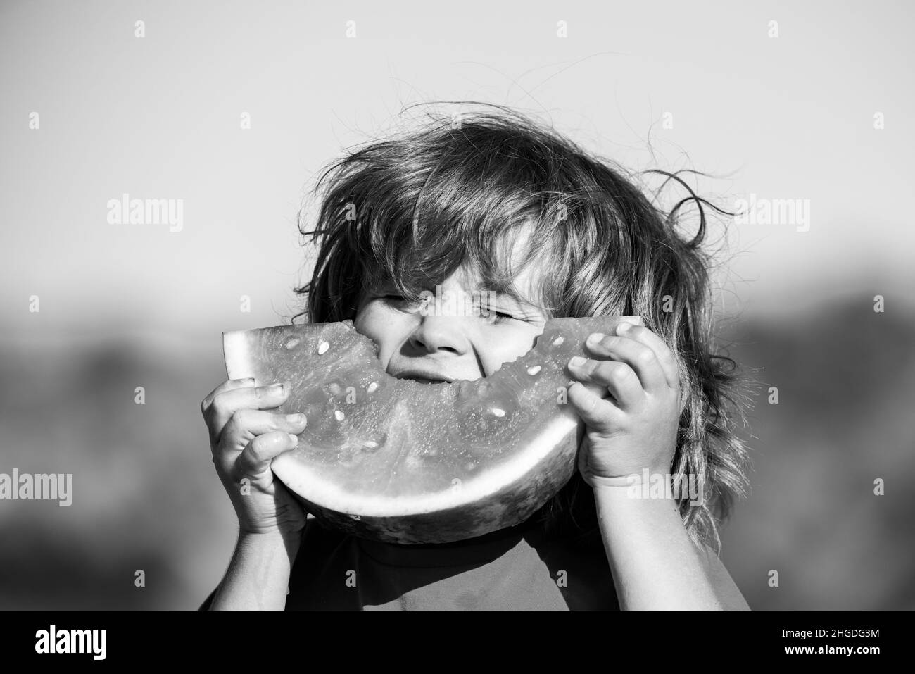 Les enfants souffrant de faim mangent de la pastèque rouge dans la bouche. Les enfants mangent du melon. Banque D'Images
