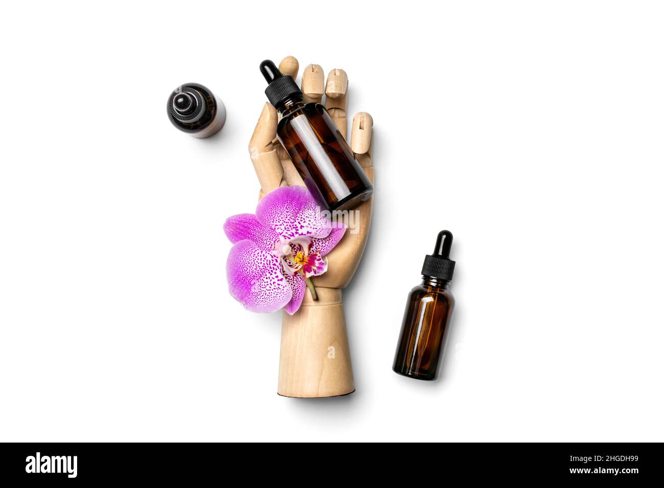 main en bois tient une bouteille de cosmétique en verre avec huile naturelle hydratante, Orchid rose isolé sur fond blanc vue du dessus Flat Lay Eco, bio, zéro déchet Banque D'Images