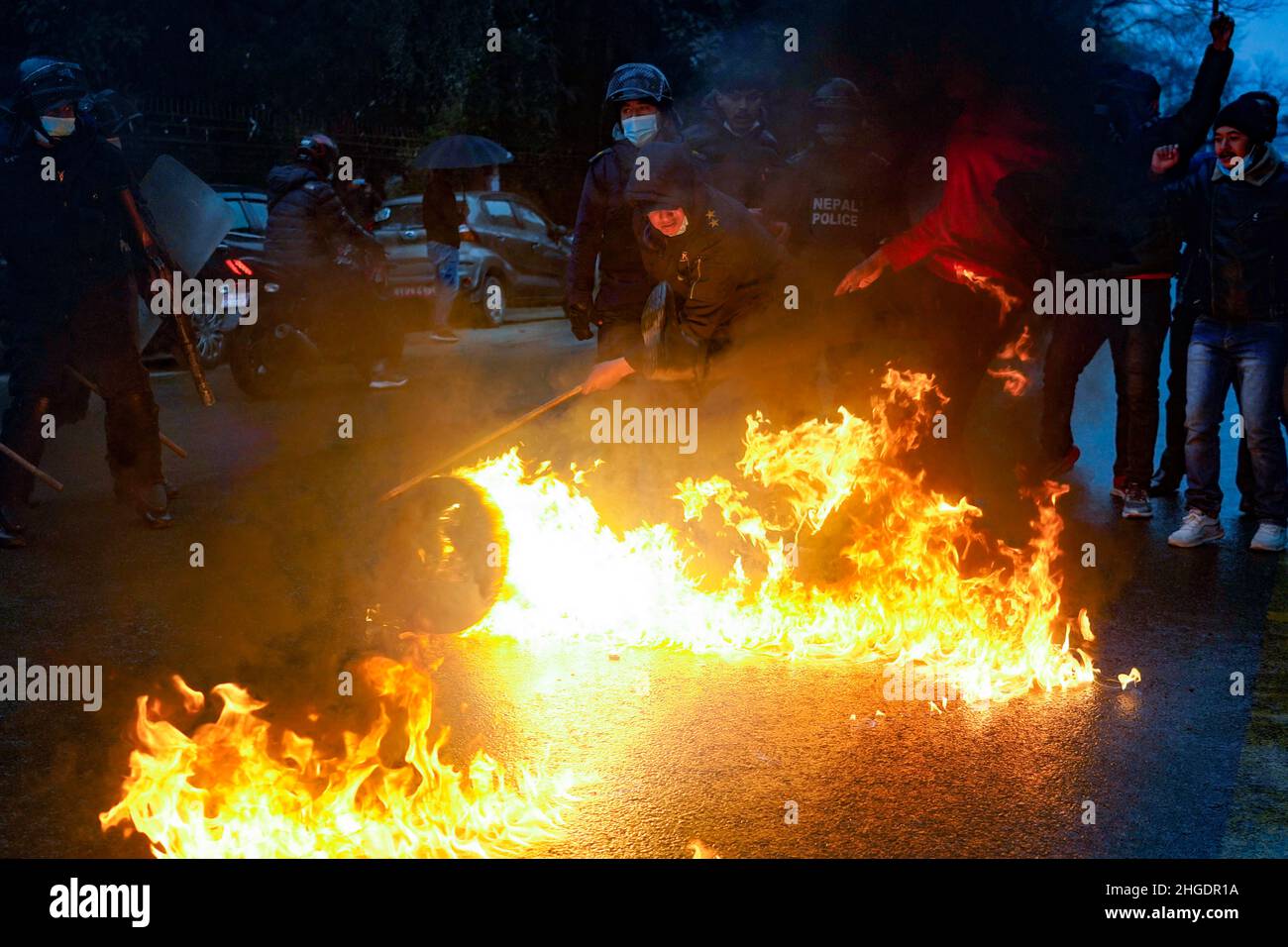 Katmandou, Népal.20th janvier 2022.Un policier anti-émeute tente d'éteindre un feu éclairé par des cadres du Parti communiste népalais lors d'une manifestation contre la hausse des prix du carburant à Katmandou, au Népal, le jeudi 20 janvier 2022.(Credit image: © Skanda Gautam/ZUMA Press Wire) Banque D'Images